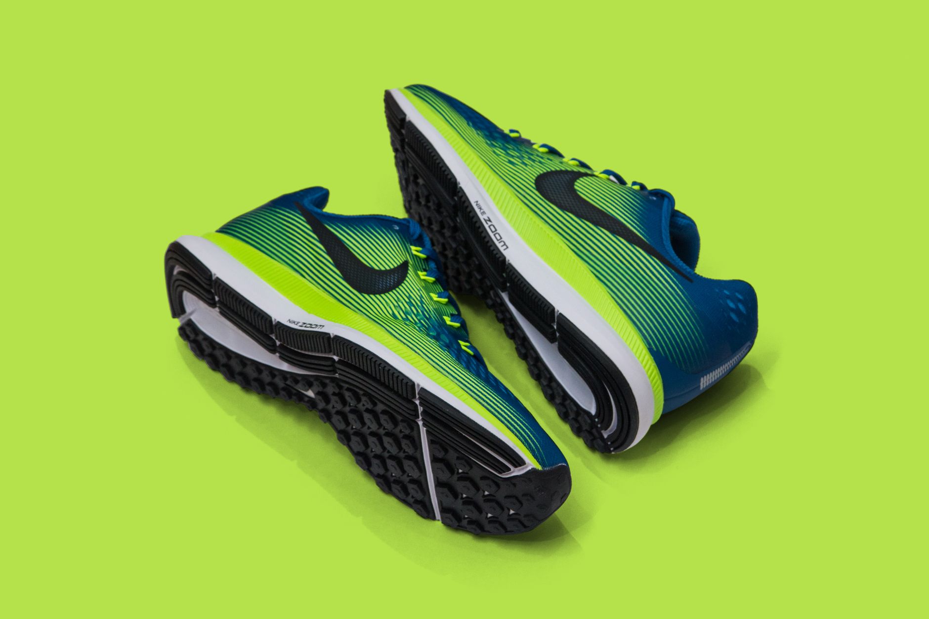 Paire de chaussures de sport bleu et vert posée sur fond uni